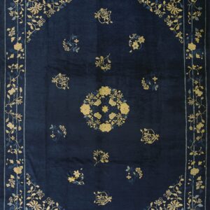 Navy blue rug featuring a low sheen and a floral pattern in gold and light blue throughout the border and field.