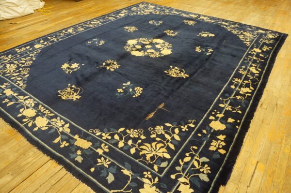 Navy blue rug featuring yellow and teal floral designs rests on golden-toned wooden planks.