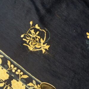 Plush navy rug with yellow floral motifs and teal accents along a visible striped border.