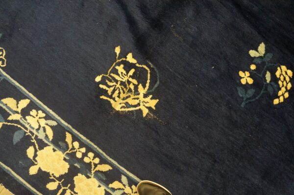 Plush navy rug with yellow floral motifs and teal accents along a visible striped border.