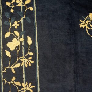 High-pile navy rug with high-contrast golden flowering vines on the border beside hardwood.