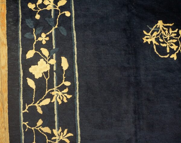High-pile navy rug with high-contrast golden flowering vines on the border beside hardwood.