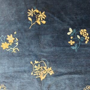 Dark blue low-pile rug with scattered golden yellow and teal floral designs.