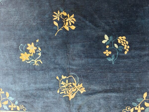 Dark blue low-pile rug with scattered golden yellow and teal floral designs.