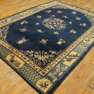 Large navy rug with detailed cream and light blue traditional motifs resting on yellow-toned plank flooring.