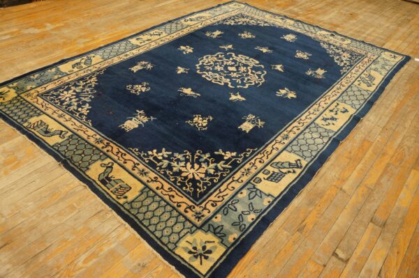 Large navy rug with detailed cream and light blue traditional motifs resting on yellow-toned plank flooring.