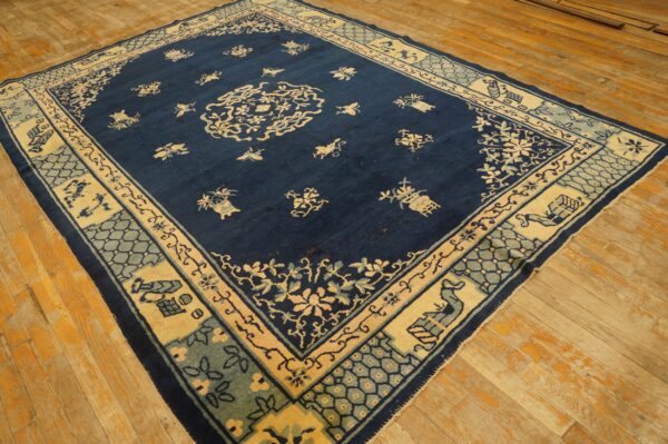 Navy blue rug with a pale yellow medallion and complex light blue borders lies on distressed wood planks.