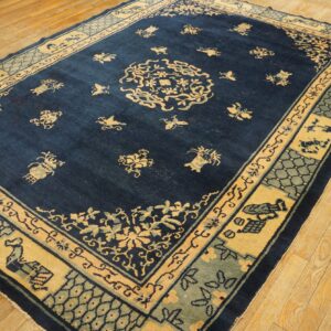 Deep blue area rug with yellow and sage medallion and border patterns on light wooden floorboards.