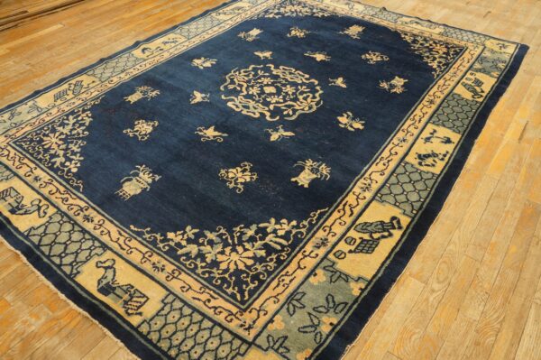 Deep blue area rug with yellow and sage medallion and border patterns on light wooden floorboards.