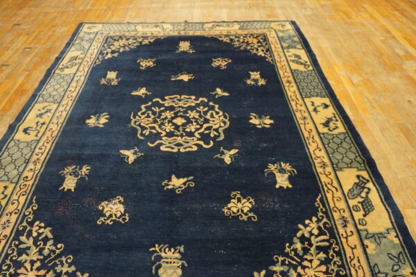 Navy blue rug with a central medallion and detailed light-colored borders, displayed on a wooden floor.