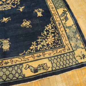 Oriental style navy blue rug with goldenrod and sage intricate border patterns on light wood planks.