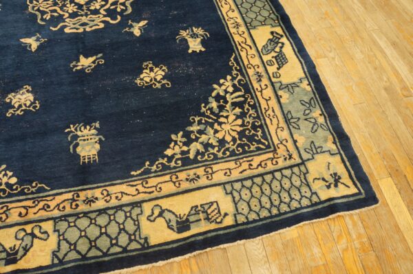 Oriental style navy blue rug with goldenrod and sage intricate border patterns on light wood planks.