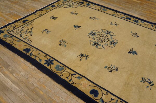 Pale yellow rug featuring scattered blue floral designs and a navy border, placed on natural hardwood floors.