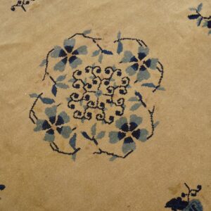 Tan rug detail displays a stylized blue and navy floral medallion surrounded by black vines.