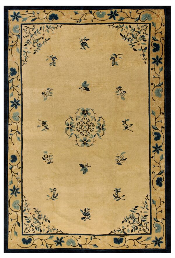 Tan rug with navy and teal floral border, a central medallion, and scattered motifs.