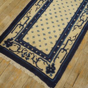 Low-pile runner rug in indigo and cream, featuring detailed borders, rests on weathered wood planks.