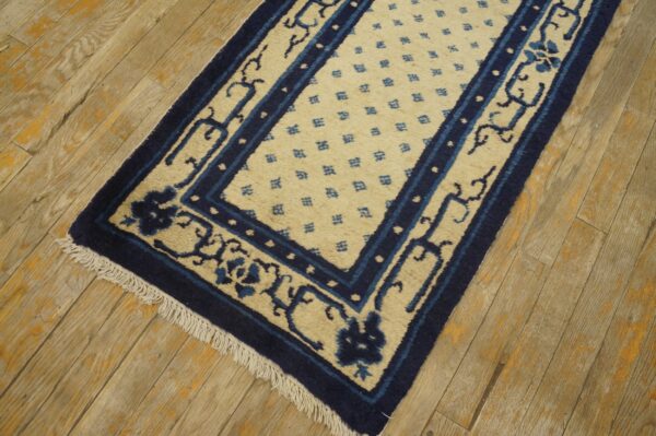 Low-pile runner rug in indigo and cream, featuring detailed borders, rests on weathered wood planks.