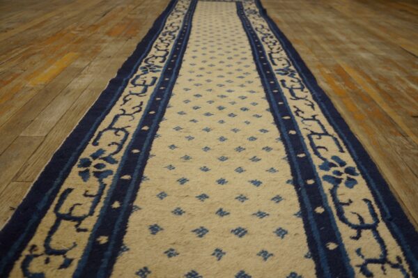 Low-pile blue and cream runner on rustic wooden floor planks.