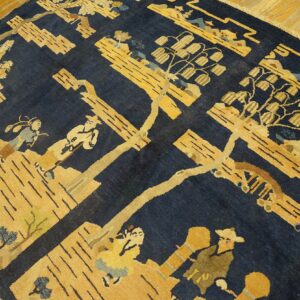 A navy blue rug with a golden yellow patterned landscape featuring stylized people and trees rests on wood flooring.