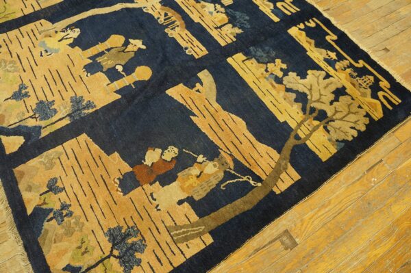 Pictorial rug in deep blue and gold with figures and trees, displayed on honey wood planks.