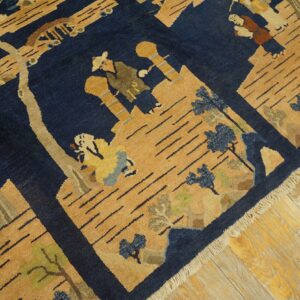 Navy blue and gold pictorial rug with stylized figures and trees rests on light wooden planks.