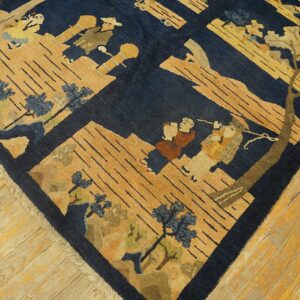 Navy blue and tan pictorial rug with human figures and trees displayed on worn light hardwood planks.
