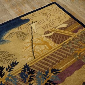 Detailed scenic rug pattern in tan, gold, navy, brown, and maroon laying on a light wood floor.