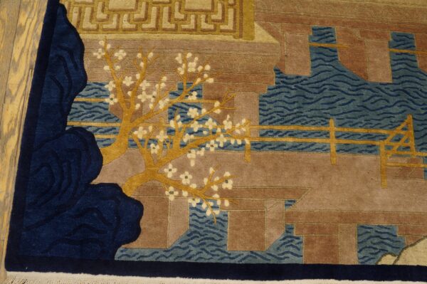 Close-up of a pictorial rug with golden cherry trees, blue water, and brown architecture on wood floors.