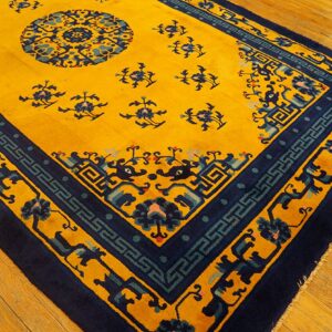 A vibrant yellow rug with dark blue patterns and teal accents rests on light brown wooden planks.