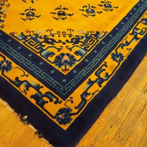 High-pile yellow rug corner detailed with intricate navy and teal patterns, shown on light wood floors.