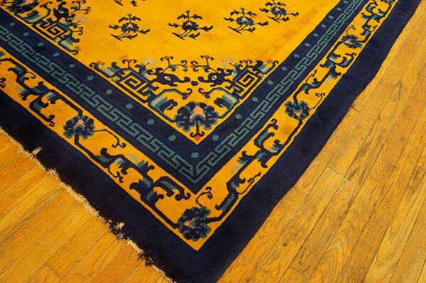 High-pile yellow rug corner detailed with intricate navy and teal patterns, shown on light wood floors.