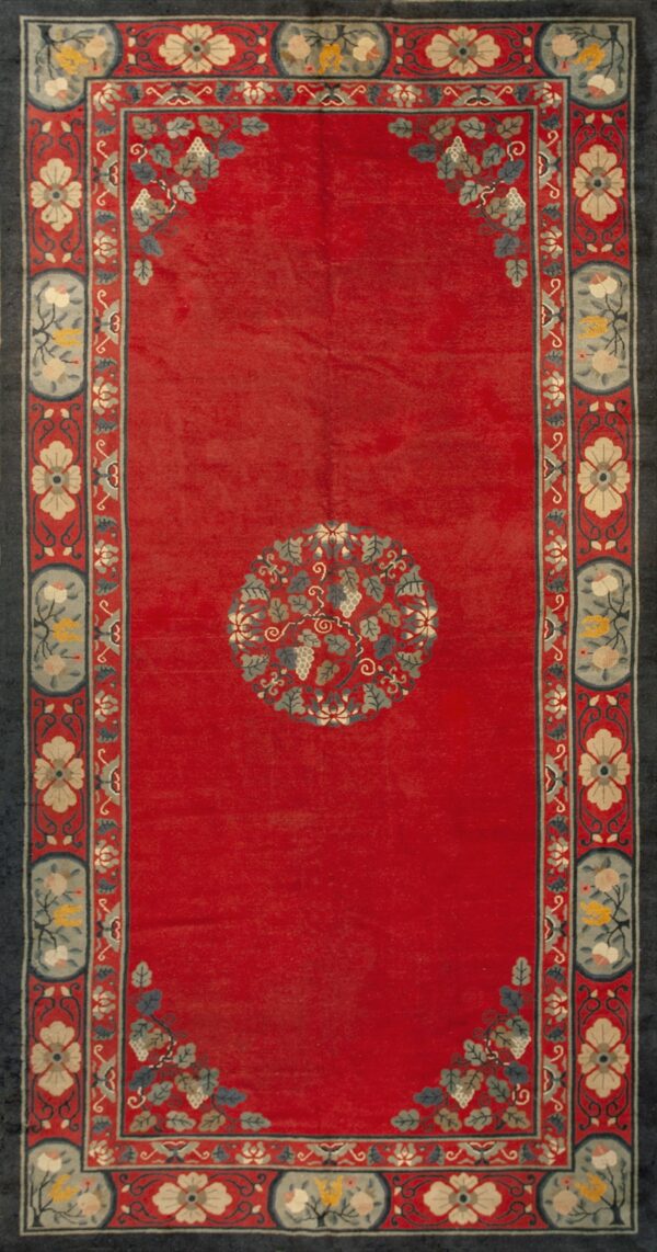 Low-pile red rug featuring a central vine medallion and wide, detailed blue and cream floral borders.
