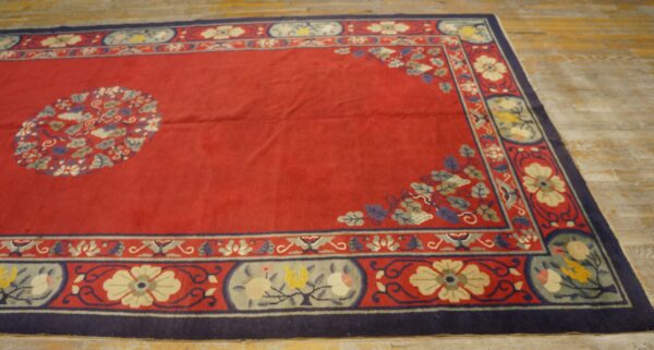 A red rug with a central medallion and complex floral border rests on light, distressed wood floors.