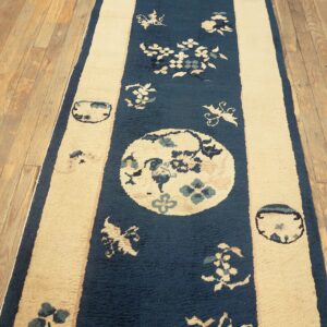 Blue and cream striped runner rug featuring floral medallions lies on light hardwood flooring.