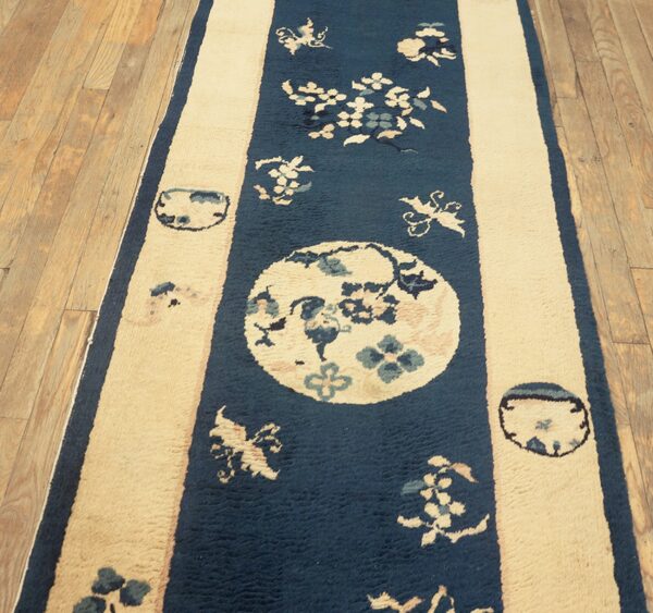 Blue and cream striped runner rug featuring floral medallions lies on light hardwood flooring.