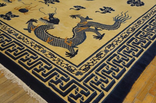 Navy blue dragon rug on a yellow field with geometric borders, lying on light brown wood flooring.