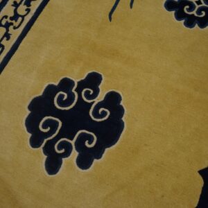 Detailed view of a yellow rug with bold indigo cloud and scale patterns outlined in cream.