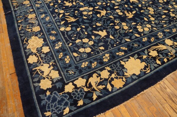 Dark blue rug with thick pile, featuring yellow and teal floral borders and birds on wood planks.