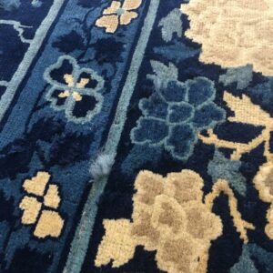 Navy and tan high-pile rug detail featuring stylized blue and beige floral designs and vertical stripes.