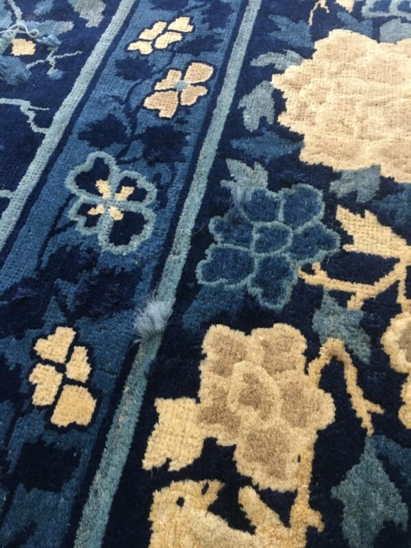 Navy and tan high-pile rug detail featuring stylized blue and beige floral designs and vertical stripes.