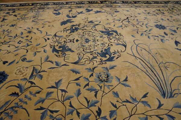 Beige rug with intricate blue botanical patterns, a central medallion, and a dark blue border.