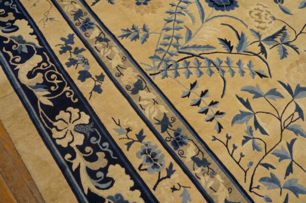 High-pile rug with a tan field and intricate deep blue floral border and vine design.