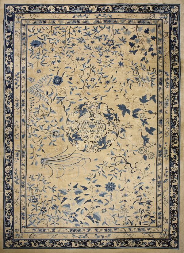 A large beige rug featuring an intricate blue floral vine pattern and a wide navy border.