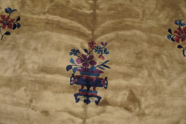 Tan high-pile rug detail showing a central purple, blue, and maroon floral vase pattern.