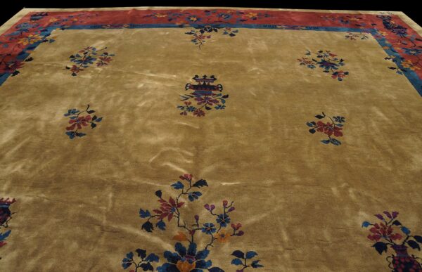Plush gold rug with scattered blue and maroon floral sprays and a wide red and blue patterned border.