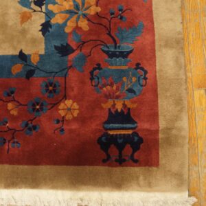 High-pile rug in rust, tan, teal, and gold floral patterns rests on worn hardwood flooring.