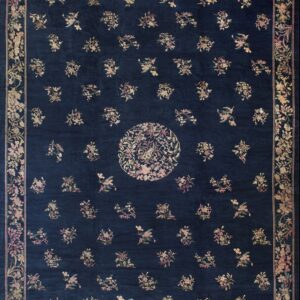 A navy blue rug featuring scattered pale floral motifs, a circular center, and a wide floral border.