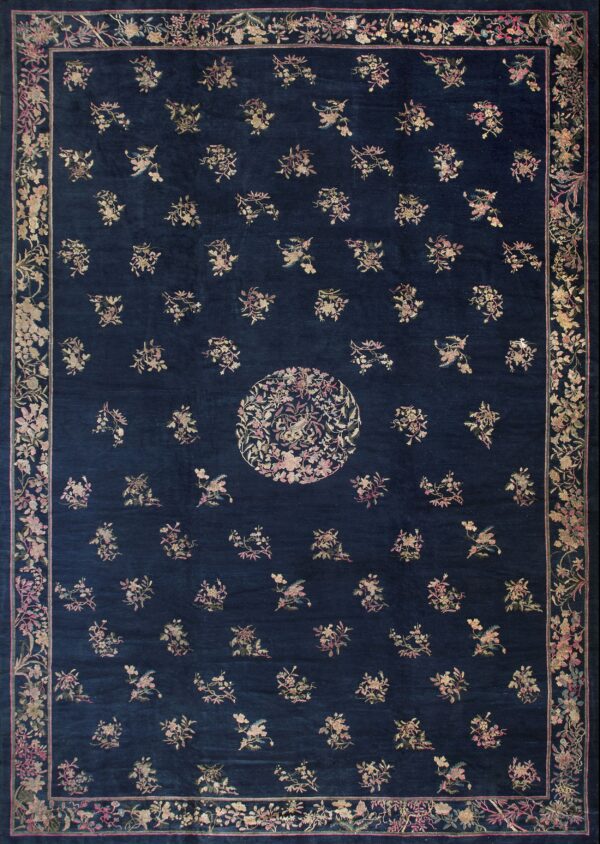 A navy blue rug featuring scattered pale floral motifs, a circular center, and a wide floral border.