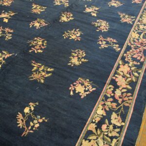 A navy blue rug with scattered light floral motifs and a detailed border rests on wood planks.