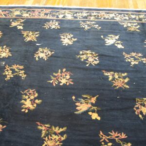 Dark blue rug with scattered pink and gold floral sprigs and a matching border on wood floors.
